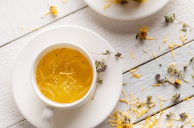 İki fincan aromatik çiçek çayı, sakinleştirici, beyaz ahşap arka planda tıbbi amaçlı.