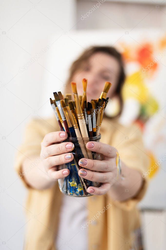 girl holding a jar with art brushes, selective focus, girl out of focus