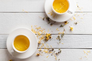 İki fincan aromatik çiçek çayı, sakinleştirici, beyaz ahşap arka planda tıbbi amaçlı.