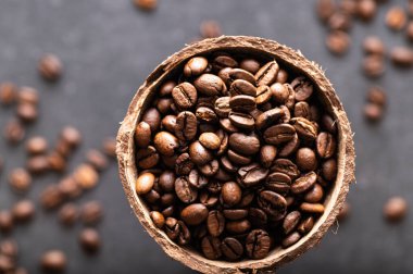 Siyah kahve çekirdekleri, hindistan cevizi kâsesinde aromatik, yakın plan.