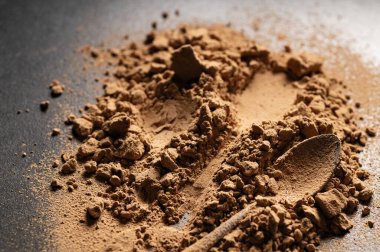 Masanın üzerindeki doğal, tatlı keçiboynuzu tozu dağılmış, metal bir kaşık izi.