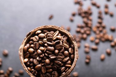 Siyah kahve çekirdekleri, hindistan cevizi kâsesinde aromatik, yakın plan.