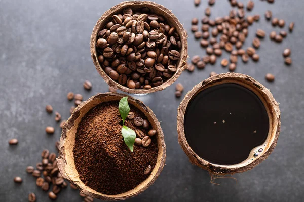 stages of preparation of black coffee, beans, ground, freshly brewed in coconut bowls, on a gray background, close-up