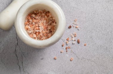 Büyük pembe himalaya tuzu, mermer arka planda çeşnilendirmek için havan topu, üst manzara.