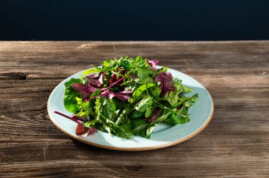 Taze otların salata karışımı, roka, İsviçre pazısı, tarenle 'de ıspanak, ahşap arka planda, üst tarafta manzara.