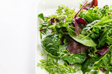 Taze otların salata karışımı, roka, pazı, beyaz arka planda bir tabakta ıspanak, yakın plan, metin için boş alan