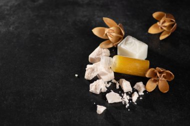 Spa prosedürleri için yağ, rahatlama, mis kokulu sabun parçaları, el yapımı, kurumuş çiçekler, zambaklar, koyu arka plan, yazı için yer, üst görünüm