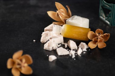 Spa prosedürleri için yağ, rahatlama, mis kokulu sabun parçaları, el yapımı, kurumuş çiçekler, zambaklar, koyu arka plan, yazı için yer, üst görünüm