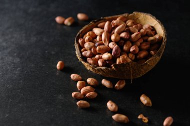 Hindistan cevizi kasesinde koyu gri arka planda yer fıstığı, kuru fıstık.