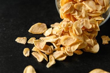 Koyu gri arka planda cam bir kasede dilimlenmiş sarımsak.