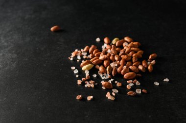 yer fıstığı, kuru yer fıstığı, koyu gri arka planda Himalaya kaba tuzu, üst manzara, metin için boş alan