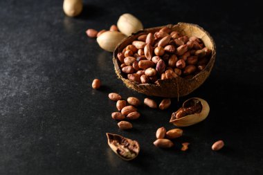 Fıstıklar, kuru fıstıklar, fındıklar Hindistan cevizi kasesinde koyu gri arka planda.