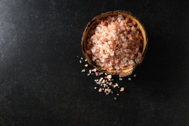 Koyu gri arka plan manzaralı hindistan cevizi kasesinde pembe himalaya kabaca tuz, metin için boş boşluk