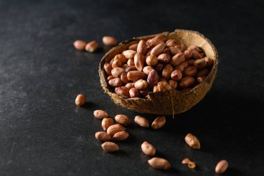 Hindistan cevizi kasesinde koyu gri arka planda yer fıstığı, kuru fıstık.