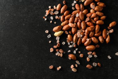 yer fıstığı, kuru yer fıstığı, koyu gri arka planda Himalaya kaba tuzu, üst manzara, metin için boş alan