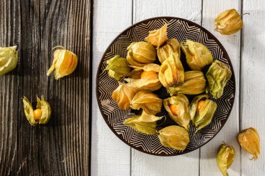 Parlak sulu sarı bitki örtüsü, beyaz ahşap bir arka planda bir tabakta uzanıyor. Üst görünüm kompozisyonu, yakın çekim.
