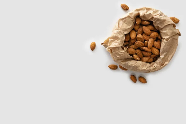 almonds in craft paper, keto food, on white background, top view, empty space for text