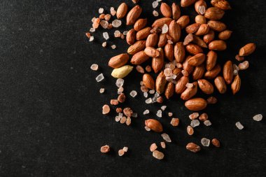 yer fıstığı, kuru yer fıstığı, koyu gri arka planda Himalaya kaba tuzu, üst manzara, metin için boş alan