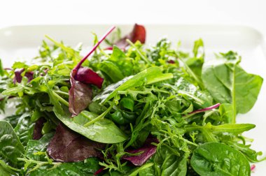 Salata karışımı taze otlar, roka, pazı, beyaz arka planda ıspanak, yakın plan.