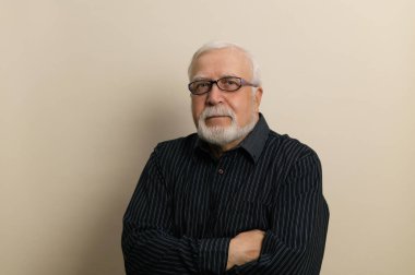 Gözlüklü ve siyah gömlekli yaşlı adam ellerini göğsüne, beline, beline, arka planına, stüdyosuna koydu.