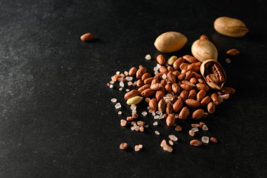 yer fıstığı, kuru yer fıstığı, ceviz, Himalaya kaba tuzu koyu gri arka planda, mesaj için boş alan