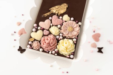 Doğal malzemelerden elde yapılmış çikolata, çiçek dekoru, beyaz arka planda üst görünüm.