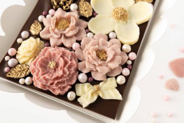 Doğal malzemelerden elde yapılmış çikolata, çiçek dekoru, üst manzara, yakın plan, beyaz arka plan.