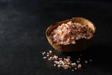 Koyu gri arka planda hindistan cevizi kasesinde pembe himalaya kaba tuzu, metin için boş boşluk