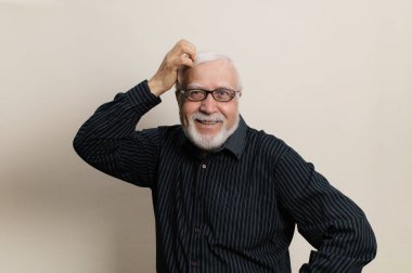 Gri saçlı, gözlüklü, gülümseyen bir adam kafasını tokuşturur ve gülümser, çerçevede duygu, yarım boy portre, açık arkaplan