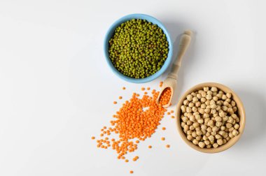 Nohut, portakallı mercimek, yeşil fasulye, beyaz bir masada seramik bir tabakta.