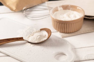 Ksentan sakızı, hamur için katkı maddesi beyaz tabakta, tahta kaşıkta, metal çırpıcıyla.