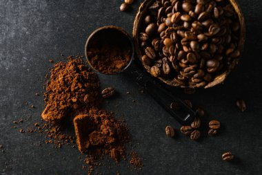 Hindistan cevizi kabında kahve çekirdekleri masaya saçılmış koyu gri arka planda, yakın planda, üst tarafta.