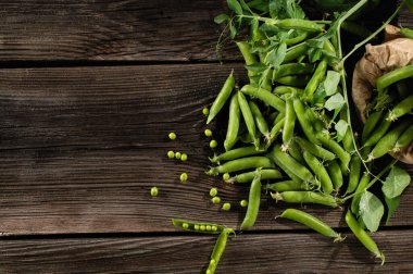 Kabuklu taze bezelyeler, eski kahverengi tahtalardan taze koparılmış, üst görünüm, metin için boş alan