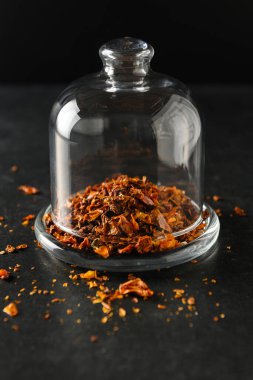 Dilimlenmiş domates, baharat, yemek malzemesi cam bir çanağın altında, gri taş bir arka planda.