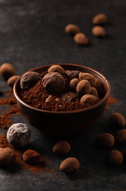 Dekoratif tabaklarda doğal çikolata trüf, karanlık arka plan, kasvetli ruh hali.