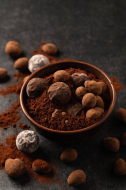 Dekoratif tabaklarda doğal çikolata trüf, karanlık arka plan, kasvetli ruh hali.