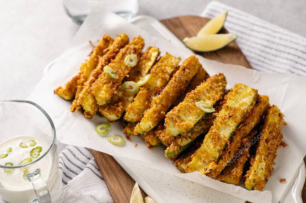 sliced zucchini baked in breading, diet appetizer, restaurant serving, sour cream sauce and lime wedges