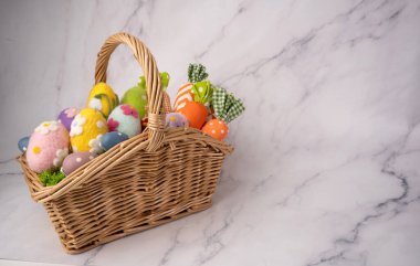 Renkli dekoratif yumurtalar ve pastel tonlarda kumaş havuçlarla dolu neşeli Paskalya sepeti. El yapımı bahar dekorasyonu beyaz arka planda izole edilmiş, Paskalya kutlamaları, tatil tasarımları, tebrik kartları, mevsimlik tanıtımlar için ideal.