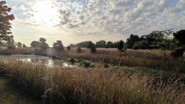 Güneş gölün üzerindeki bulutların arkasında görünür.