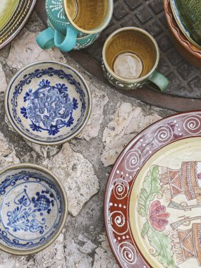 Yerel bir markette düzenlenmiş renkli el yapımı seramik kaseler, tabaklar ve fincanlar. Canlı el boyaması desenler ve tasarımlar. İçeriğiniz için arka plan, tasarımlar, reklam. Serinin vuruşu..