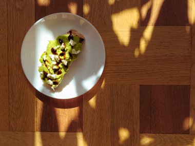 Teriyaki soslu, mayalı ekmeğe baharatlı avokado ezilmiş. Proteinli vejetaryen gıda konsepti. Ahşap arka plan ve güneş ışığı. Guacamole. Uzayı kopyala Dizinin bir parçası