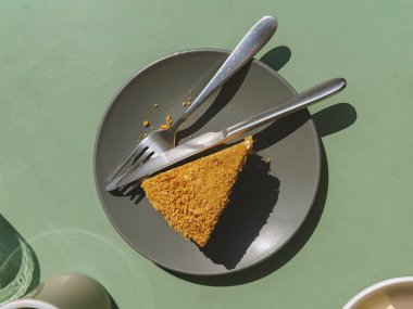 Bir dilim lezzetli ballı kek Medovik, yeşil metal sehpada çatal bıçak takımı, brunch 'ın dışında, düz yerde. Mesaj için yer var. Güneş ışığı. Fırın, restoran ve kafeterya için içerik. Dizinin bir parçası