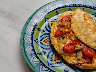 Kahvaltıda. Domatesli omlet, zeytin ve yeşil üzerine teriyaki sosu, açık mermer masada renkli tabaklar. Sağlıklı kahvaltı. Dizinin bir parçası. Üst Manzara. Boşluğu kopyala.