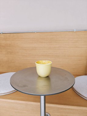 Sarı kahve ya da kapuçino. Yumuşak yastıklı bir demet yastığın önünde metal yuvarlak bir masanın üzerinde yarı sarhoş halde duruyor. Yan görüş, kopyalama alanı. Kahve dükkanı, sıcak içecek konsepti. Bir serinin parçası.