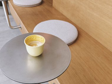 Sarı kahve ya da kapuçino. Yumuşak yastıklı bir demet yastığın önünde metal yuvarlak bir masanın üzerinde yarı sarhoş halde duruyor. Yan görüş, kopyalama alanı. Kahve dükkanı, sıcak içecek konsepti. Bir serinin parçası.