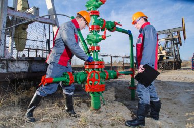 Pompa jakı ve kuyu kafası yakınında Petrol sahası işçileri