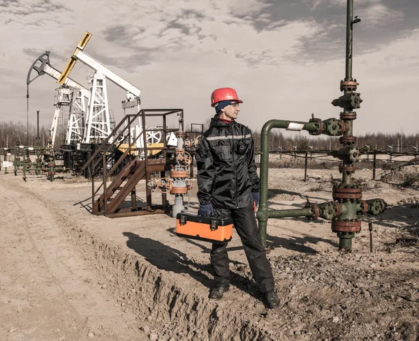 Kuyu kafası ve pompa jakı yakın Petrol sahası işçisi — Stok fotoğraf