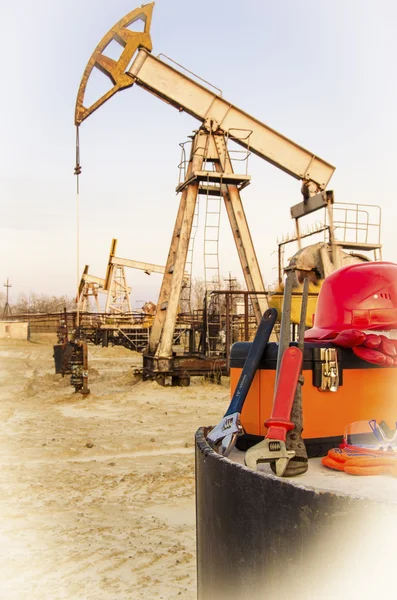 Caja de herramientas, casco y llaves en el campo petrolero — Foto de Stock