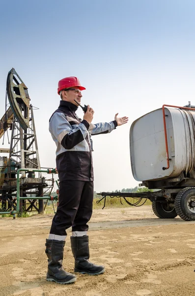 Trabajador cerca de calabaza y remolque tanque en el campo petrolífero . — Foto de Stock