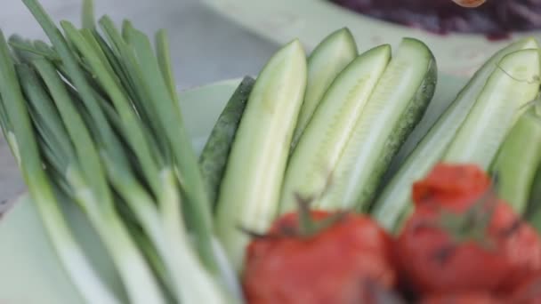 Červená rajčata a zelené okurky s cibulí a zelený salát — Stock video